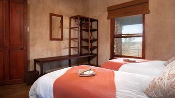 Un dormitorio con dos camas, un armario de madera, una estantería y un ventanal con vistas.