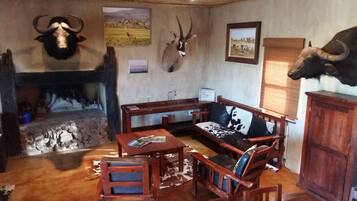 A rustic room with a stone fireplace, wooden furniture, and mounted animal heads on the walls.