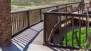 A giraffe head mounted on a wooden structure with a view of a desert landscape. - Gannabos Guest House (Gariep)