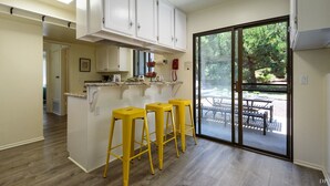 A kitchen with white cabinets, a countertop, and three yellow stools.