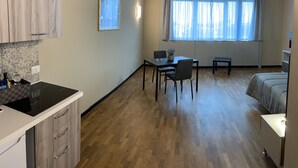 A compact room with a kitchenette, a dining area, and a bed.