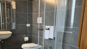A modern bathroom with a glass-enclosed shower, a toilet, a bidet, and a sink.