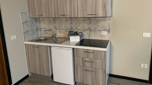 A compact kitchen with wooden cabinets, a built-in dishwasher, and a granite backsplash.