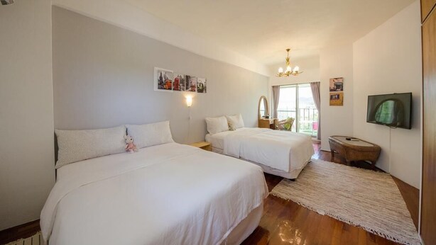 A bedroom with two beds, a chandelier, a flat-screen TV, and a small rug. - J&J B&B (Hengchun)