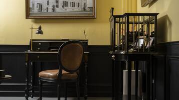 A room with a desk, a chair, a lamp, and a framed picture on the wall.