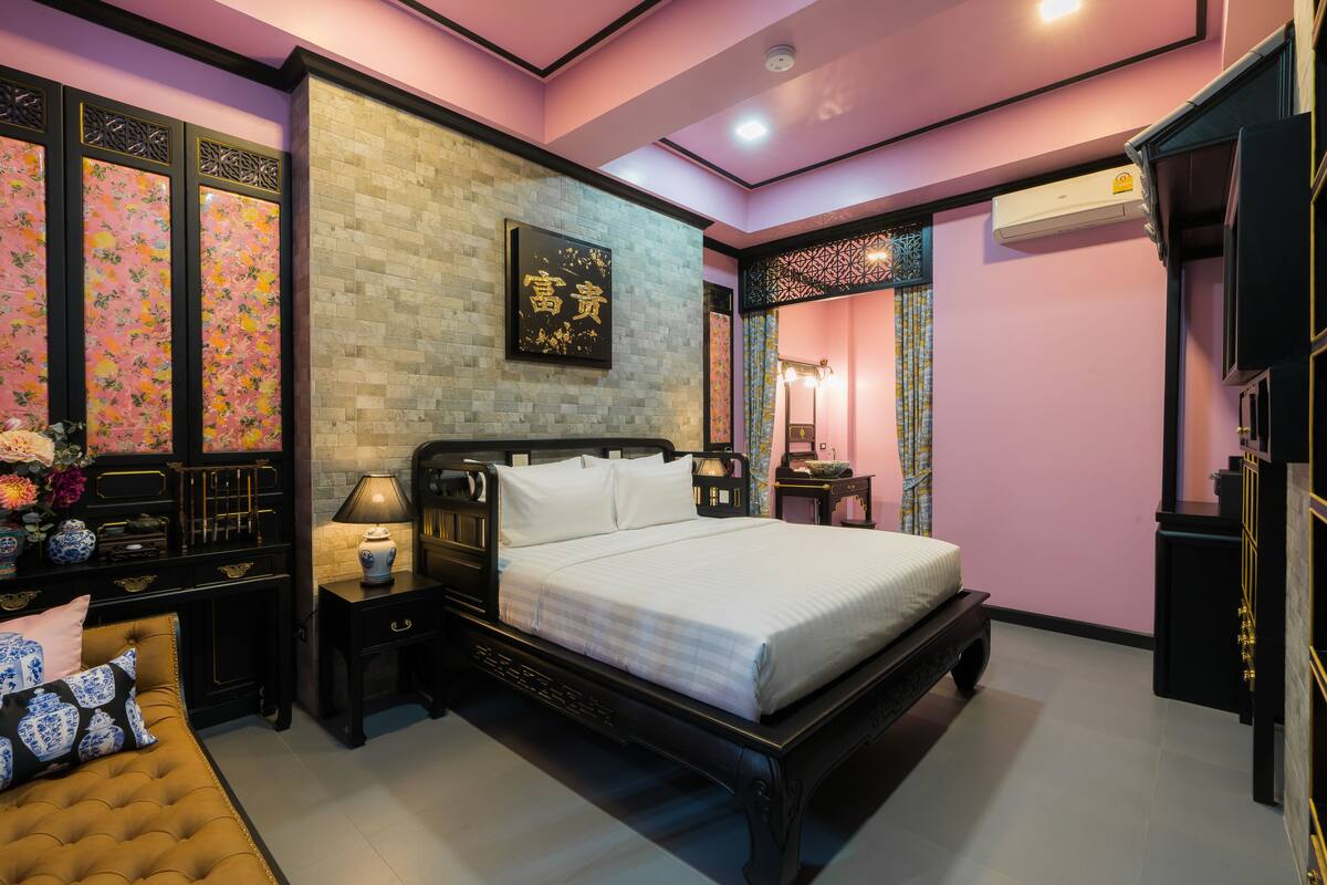 Un dormitorio con cama, mesitas de noche, armario y una pared decorativa.