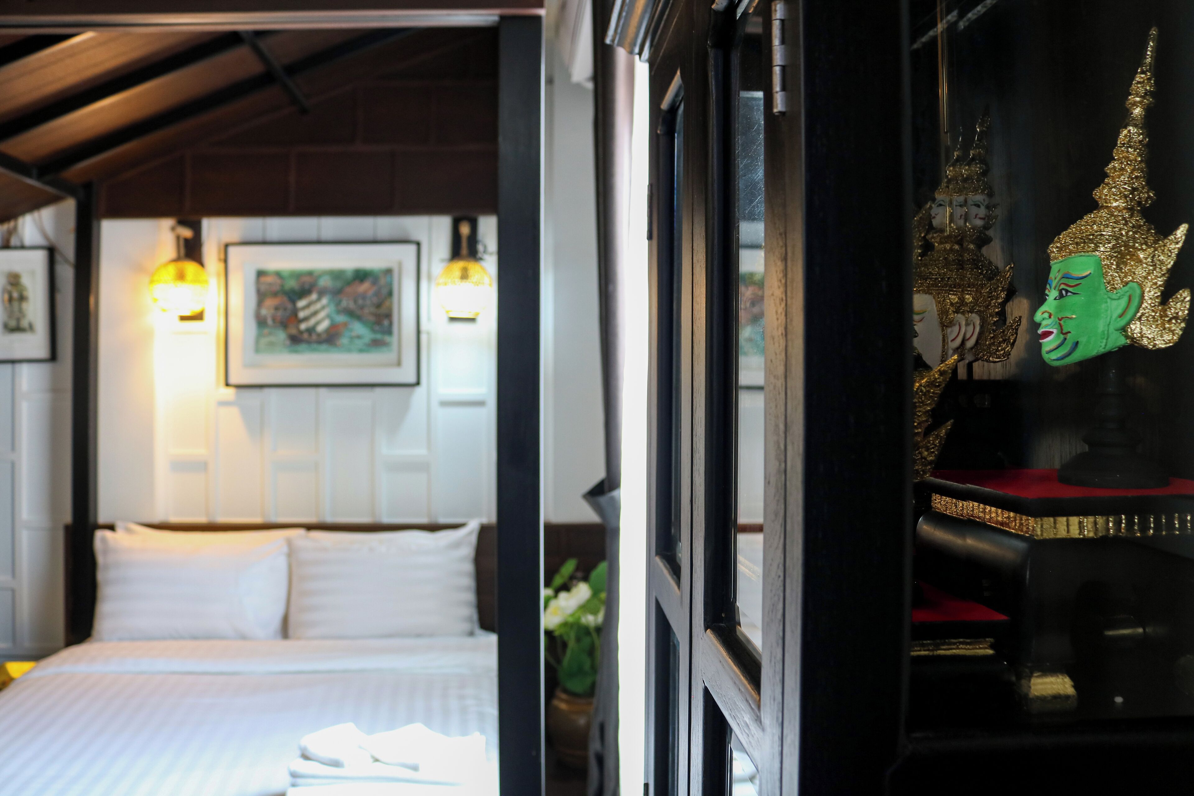 Een hotelkamer met een bed, een inlijsting foto aan de muur en een raam met uitzicht op een Boeddhabeeld.