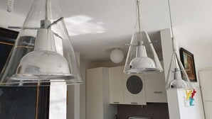 Una cucina con mobili bianchi, un forno a microonde e lampade a sospensione.