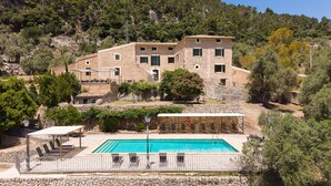 A stone building with a pool, outdoor seating, and a view of a hillside. - 44066 Finca Biniforani Nou (Buñola)