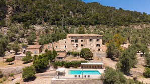 A stone building with a pool, surrounded by trees and hills. - 44066 Finca Biniforani Nou (Buñola)