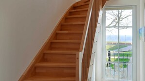 Un escalier en bois avec une porte en verre donnant sur un espace extérieur.