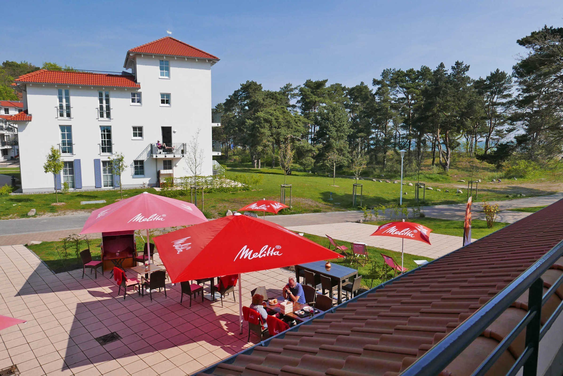 Ein Straßencafé mit roten Sonnenschirmen, Tischen und Stühlen.