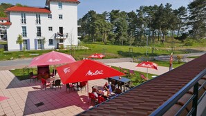 Un espace café en plein air avec des parasols rouges, des tables et des chaises.