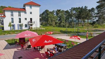 Ein Straßencafé mit roten Sonnenschirmen, Tischen und Stühlen.