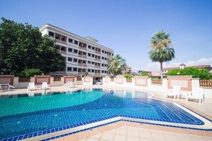 Una piscina amb vora de rajola, envoltada de gandules i palmeres.