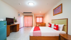 A hotel room with a bed, a desk with a television, a small table, and a chair. - OYO 917 PK Residence Pattaya (Pattaya)