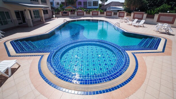 A swimming pool with a tiled edge, surrounded by lounge chairs and a tiled deck. - OYO 917 PK Residence Pattaya (Pattaya)