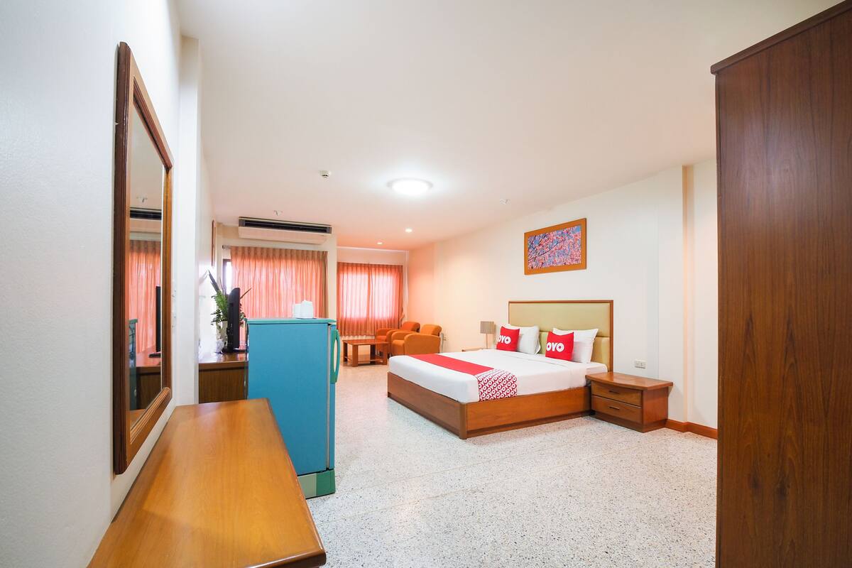 Una habitació d'hotel amb llit, taula de nit, escriptori, cadira i armari.