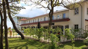 Ein Gebäude mit rotem Ziegeldach, zahlreichen Fenstern und einer überdachten Außenbereich mit Bäumen und Rasen.