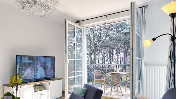 Ein modernes Wohnzimmer mit Fernseher, Sofa und Esstisch.