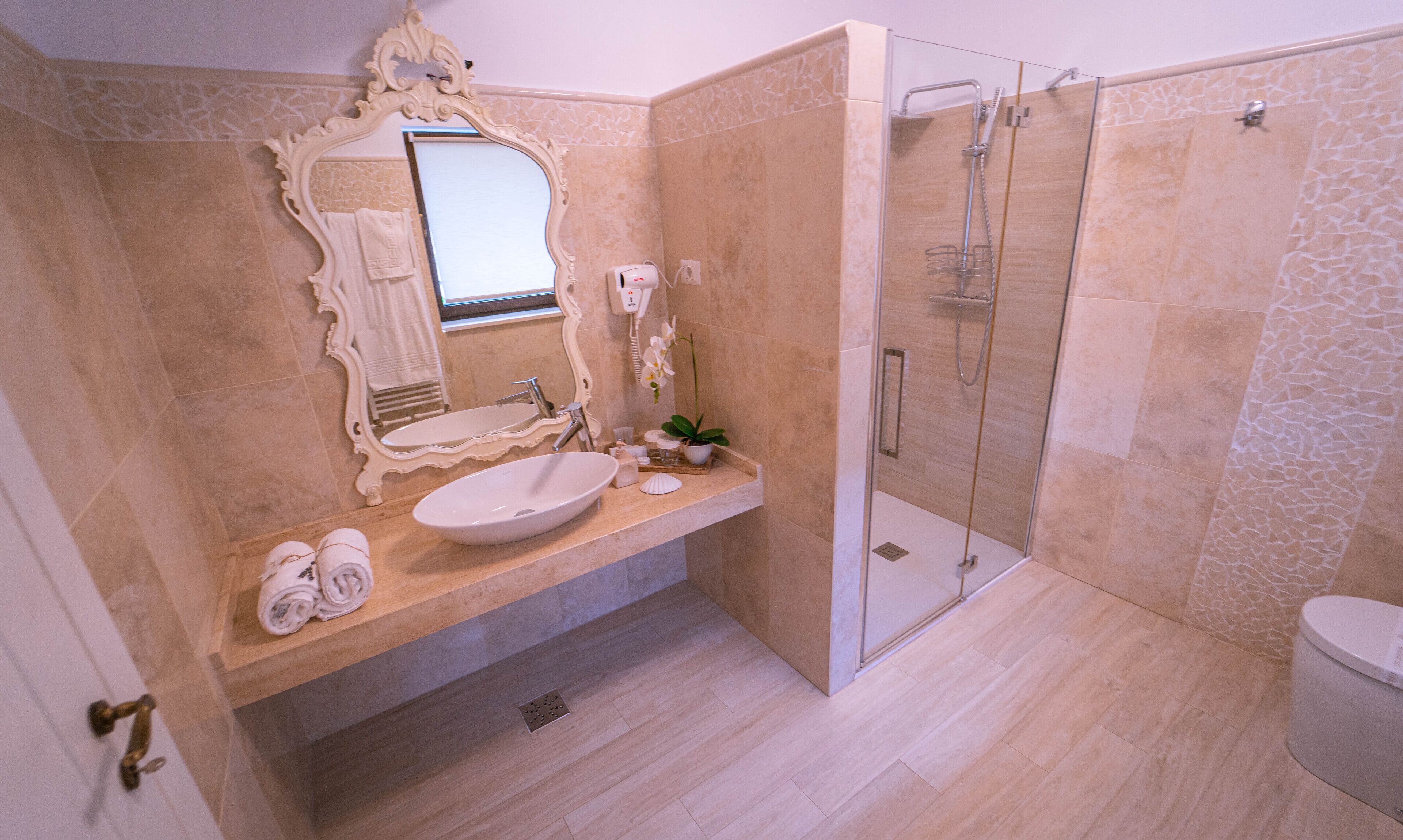 A bathroom with a large mirror, a sink, a shower, and a toilet.