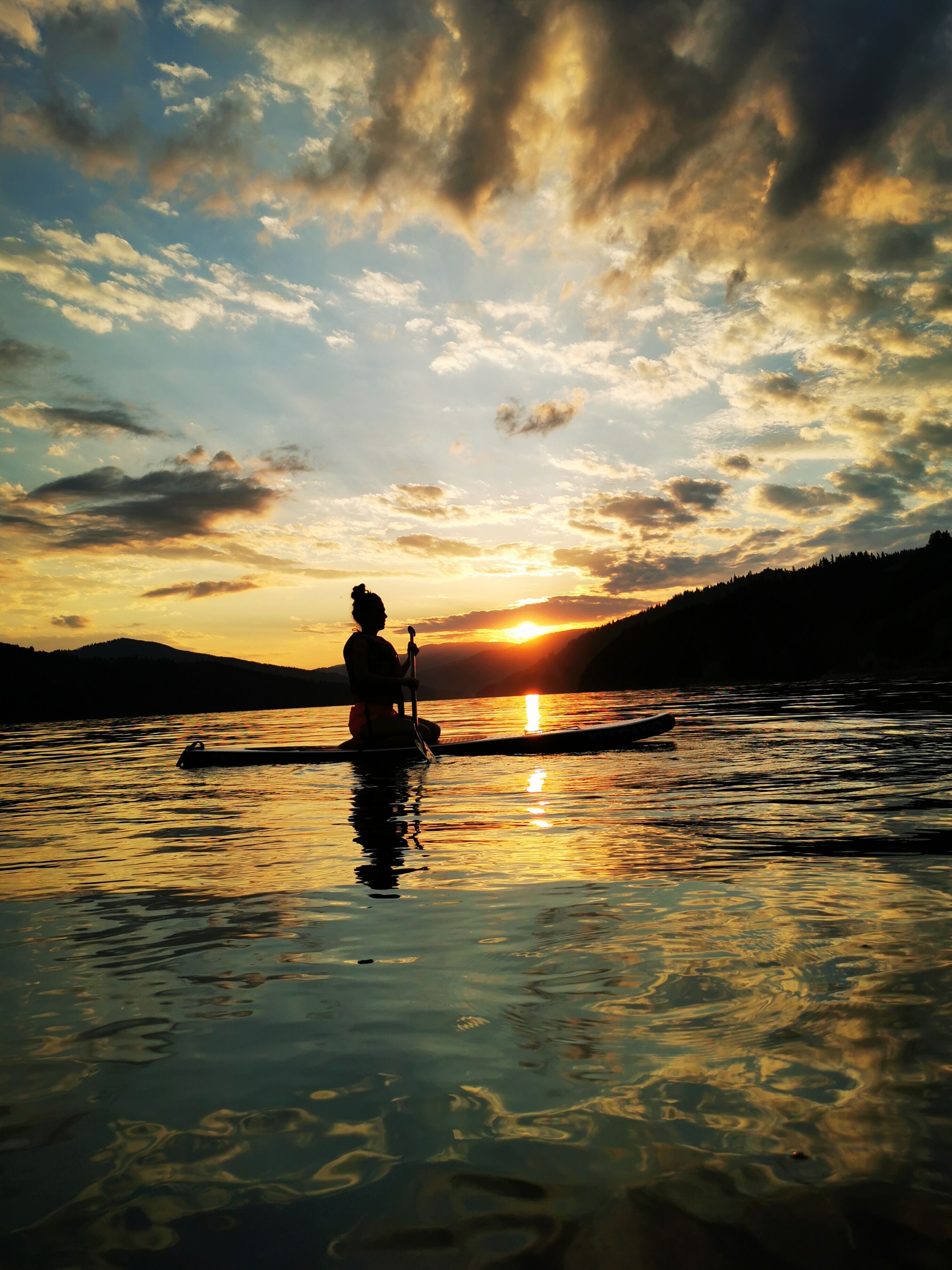 Una persona practica kayak en aguas tranquilas al atardecer.