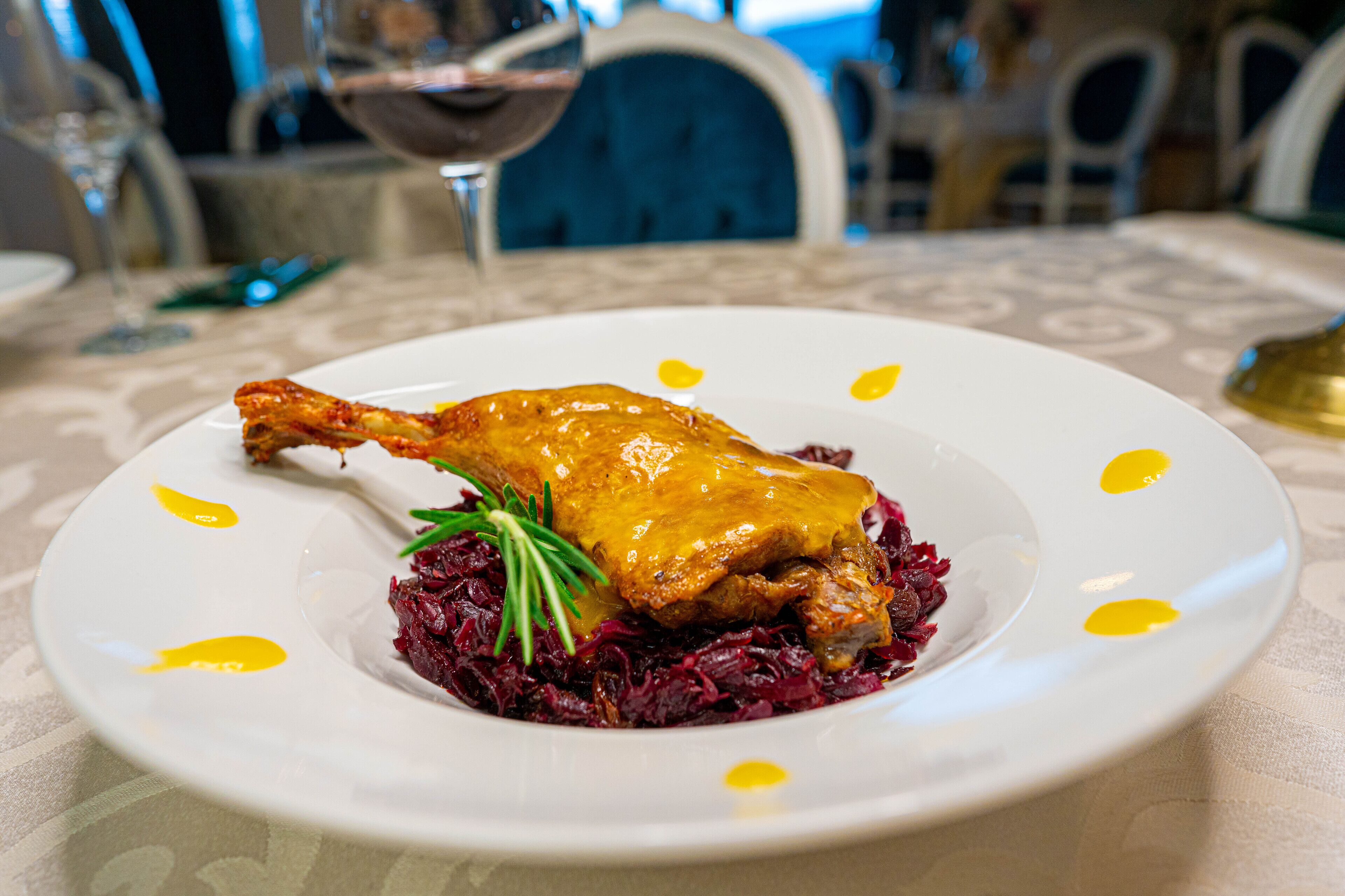 A plate with a roasted chicken leg and red cabbage, served on a white plate with yellow accents.