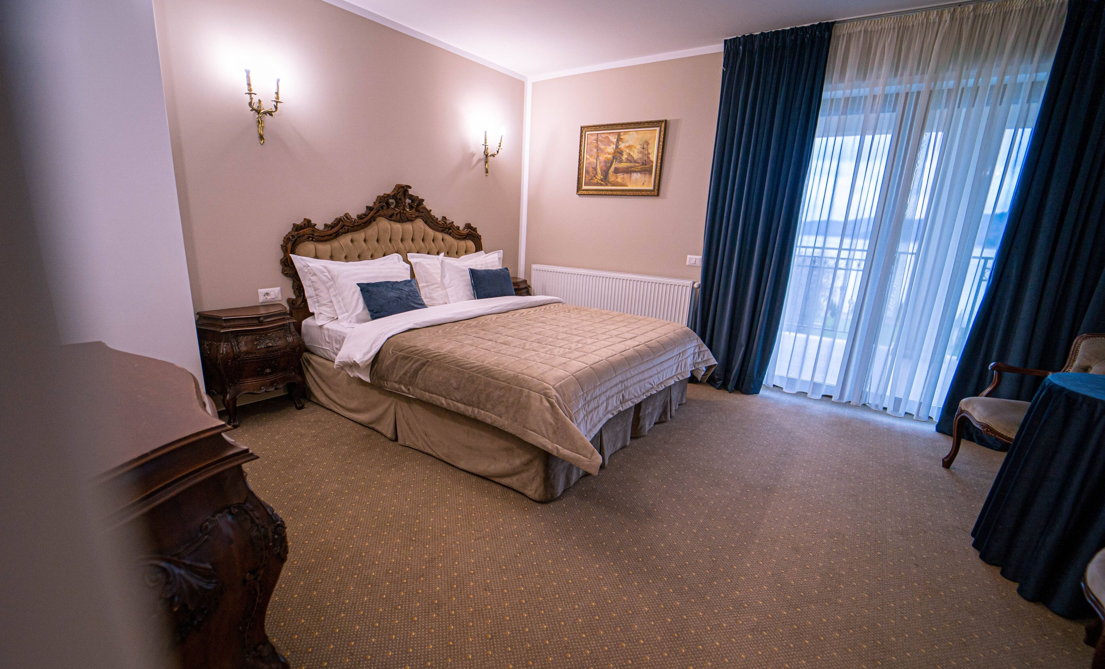 A hotel room with a bed, a dresser, a chair, a painting, and a window with curtains.
