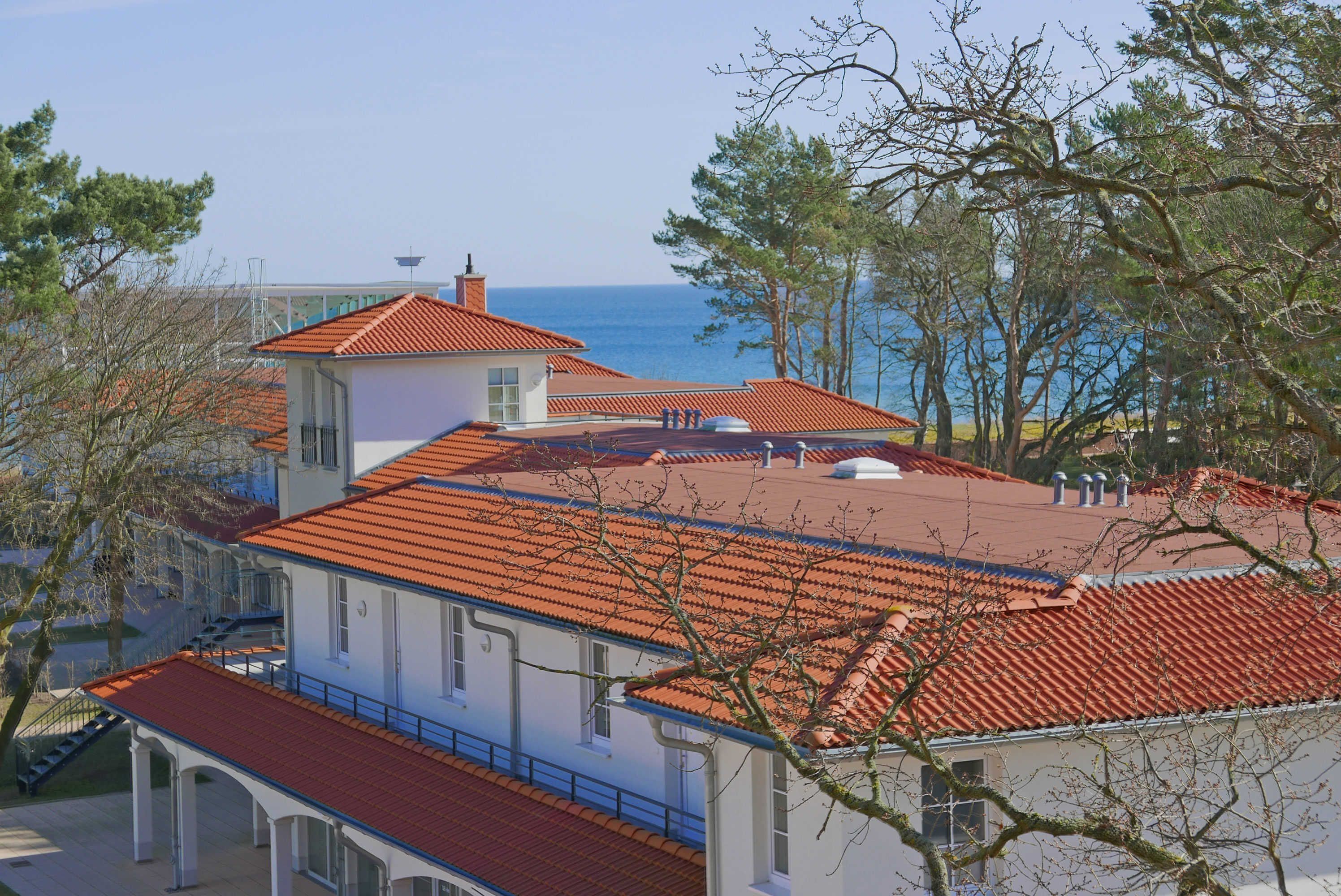 A coastal building with a red-tiled roof, white walls, and a view of the sea.