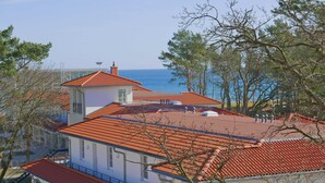 Un bâtiment situé sur la côte, avec un toit recouvert de tuiles rouges, des murs blancs et une vue sur la mer.