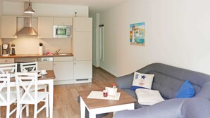 Un espace de vie compact comprenant un coin cuisine, un coin repas et un coin salon.