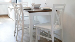 A dining table with white chairs, a bowl, and two wine glasses. - Baabe Inselparadies Fewo Bernstein Ref. 213719 u 3 - Fewo Bernstein Ref. 213719 u 3 (Sellin)