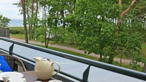 Une table dressée avec de la vaisselle blanche et une carafe, donnant sur un espace verdoyant avec des arbres et un sentier.