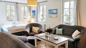 Un salon moderne avec un lit, deux canapés, une table basse et un tableau au mur.