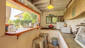 A rustic kitchen with wooden counters, a bar stool, a trash bin, and a window overlooking greenery. - 16 Mi to Beaches & Wineries! Chic Peaceful Retreat (Santa Paula)