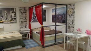 A bedroom with a four-poster bed, a desk, and chairs. There is a radiator under the bed and a window with curtains. - Apartament w Centrum Noclegi Płock (Plock)