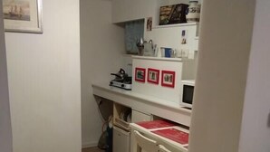 A small kitchen with a white countertop, a sink, and a stove. There are three framed pictures on the wall above the counter. - Apartament w Centrum Noclegi Płock (Plock)