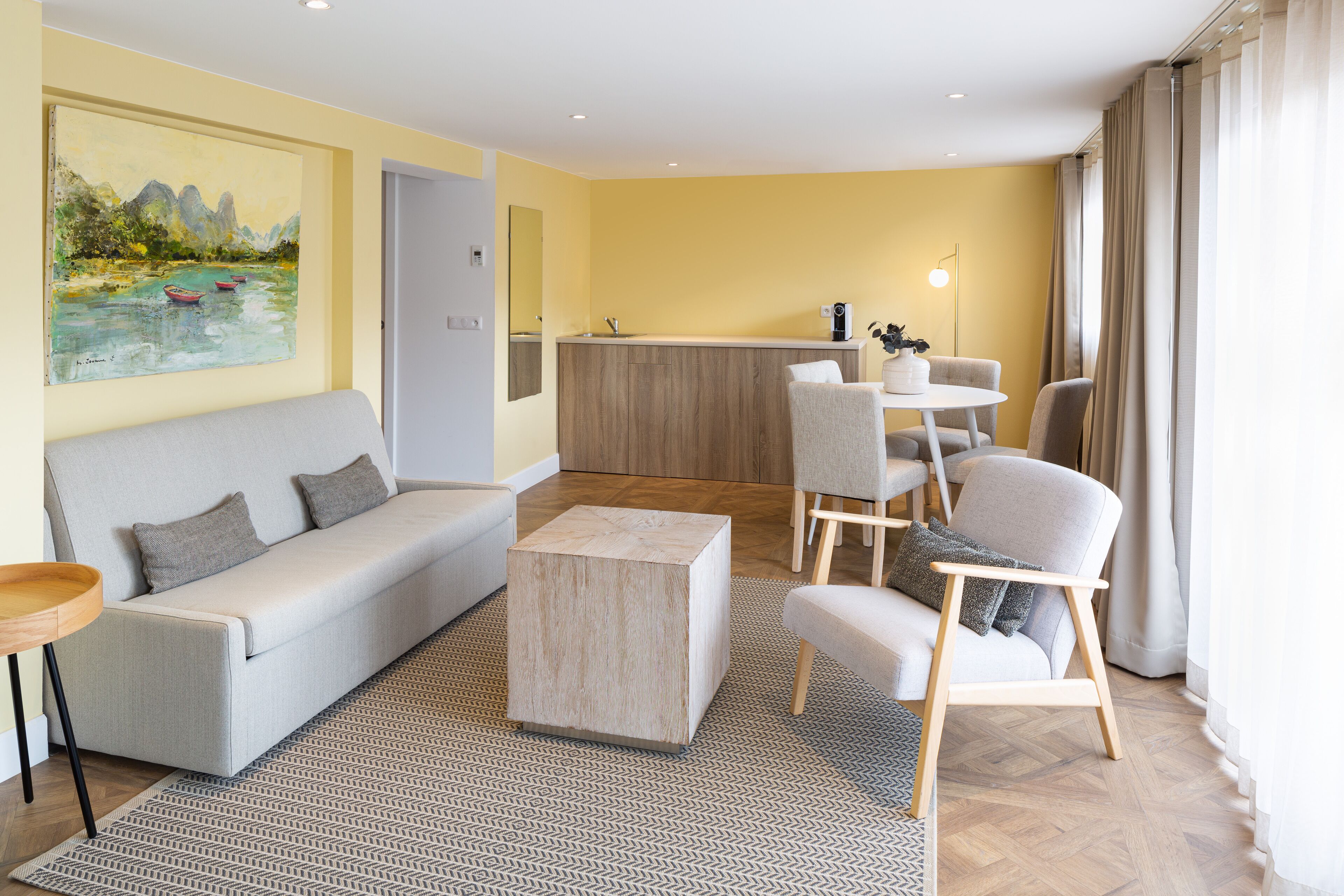Ein modernes Wohnzimmer mit einer Couch, Sesseln, einem Couchtisch und einem Gemälde an der Wand.