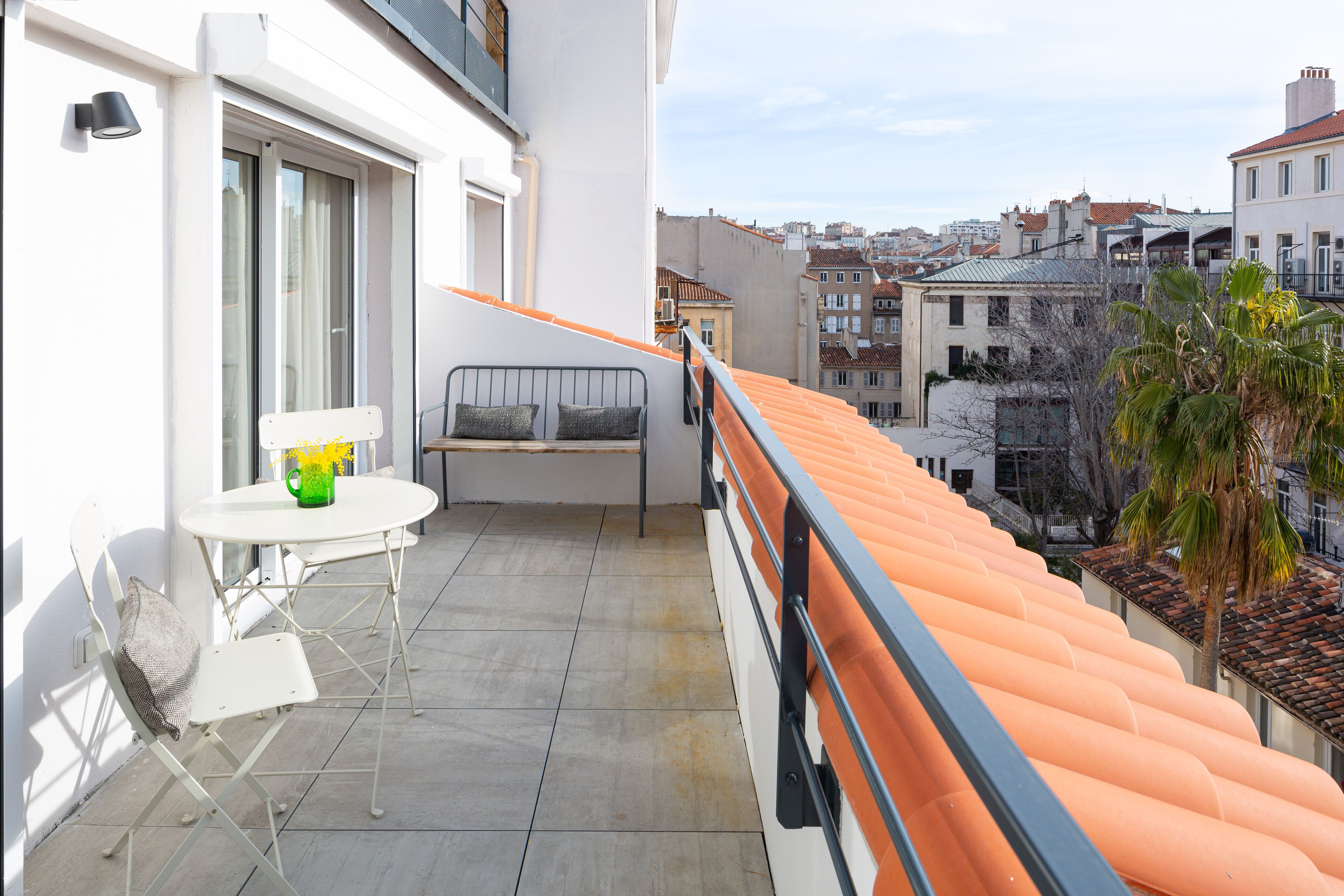 A balcony with a white table, a chair, and a sofa.