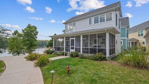 A two-story house with a covered porch, a visible fire hydrant, and a lake view.