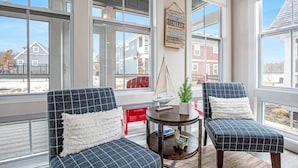 A cozy seating area with two chairs and a small table, large windows, and a view of buildings outside. - Breathtaking River View (Ottawa)