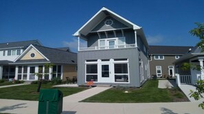 A two-story residential building with a balcony, large windows, and a well-maintained lawn.