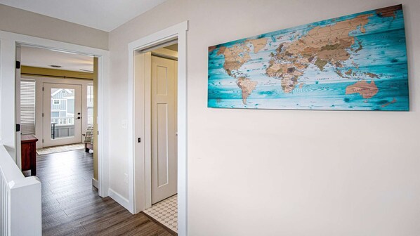 Un couloir orné d’une fresque représentant une carte du monde, une porte donnant sur une autre pièce et un plancher en bois.
