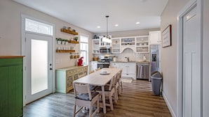 A kitchen with white cabinets, a dining table with chairs, a microwave, a stove, and a refrigerator. - Breathtaking River View (Ottawa)