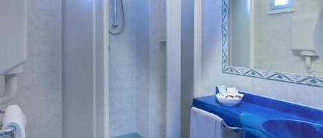 A bathroom with a glass-enclosed shower, a white toilet, a sink, and a mirror with decorative tiles.