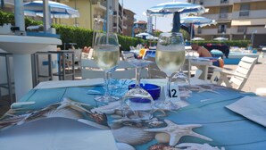 A table with two glasses of white wine, a number 12 sign, and various seashells. - Hotel Concord (Ravenna)