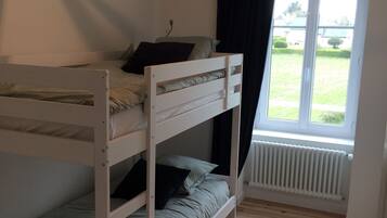 A bunk bed room with a window, a radiator, and a hanging light fixture.
