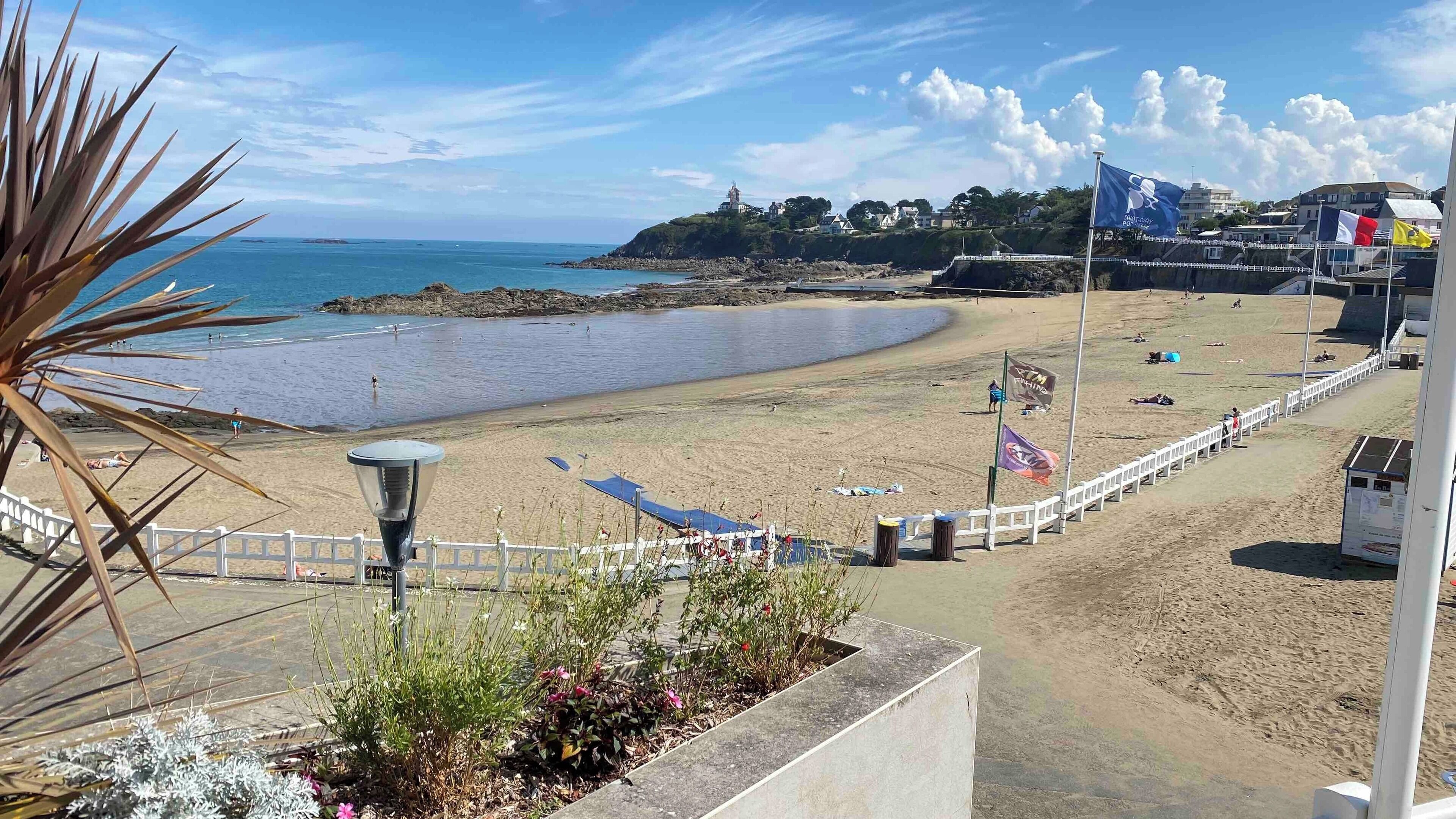 Una playa con una cerca blanca, un farol y una bandera.
