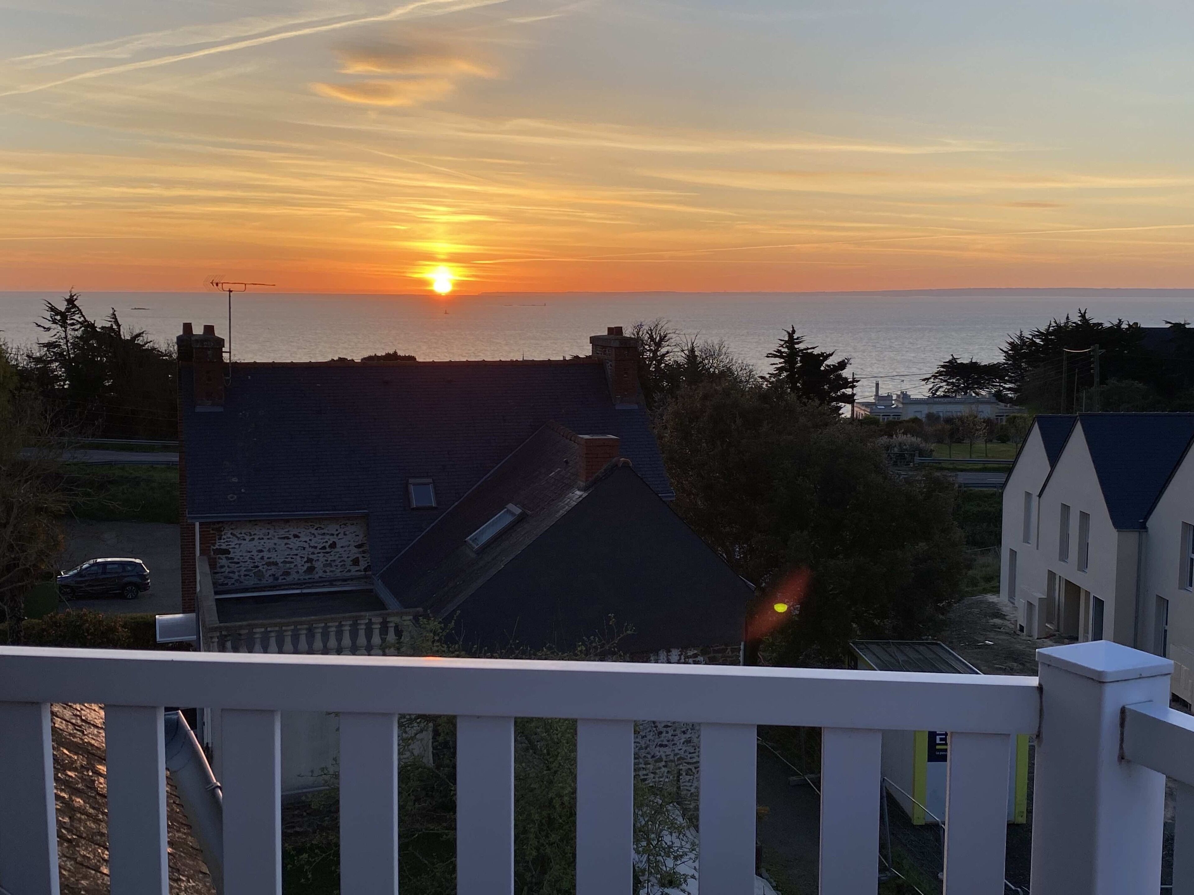 Un quartiere residenziale con case, un balcone e un tramonto sul mare.