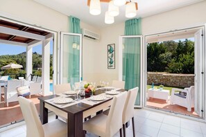 A dining area with a table set for four, a view of the outdoors, and a glass door leading outside.